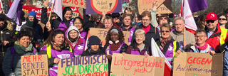 Ein Gruppenbild von Frauen beim 8. März mit Schildern. 